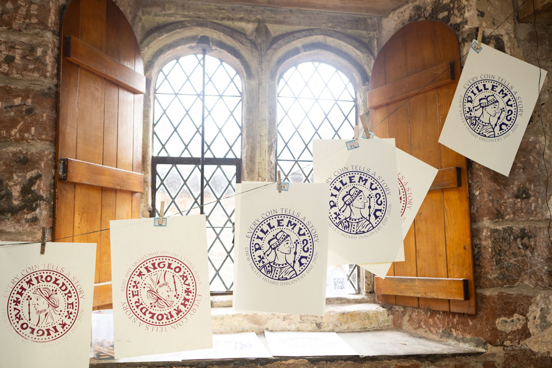 Screen print artworks hanging on a line in front of an old-fashioned window with wooden shutters.
