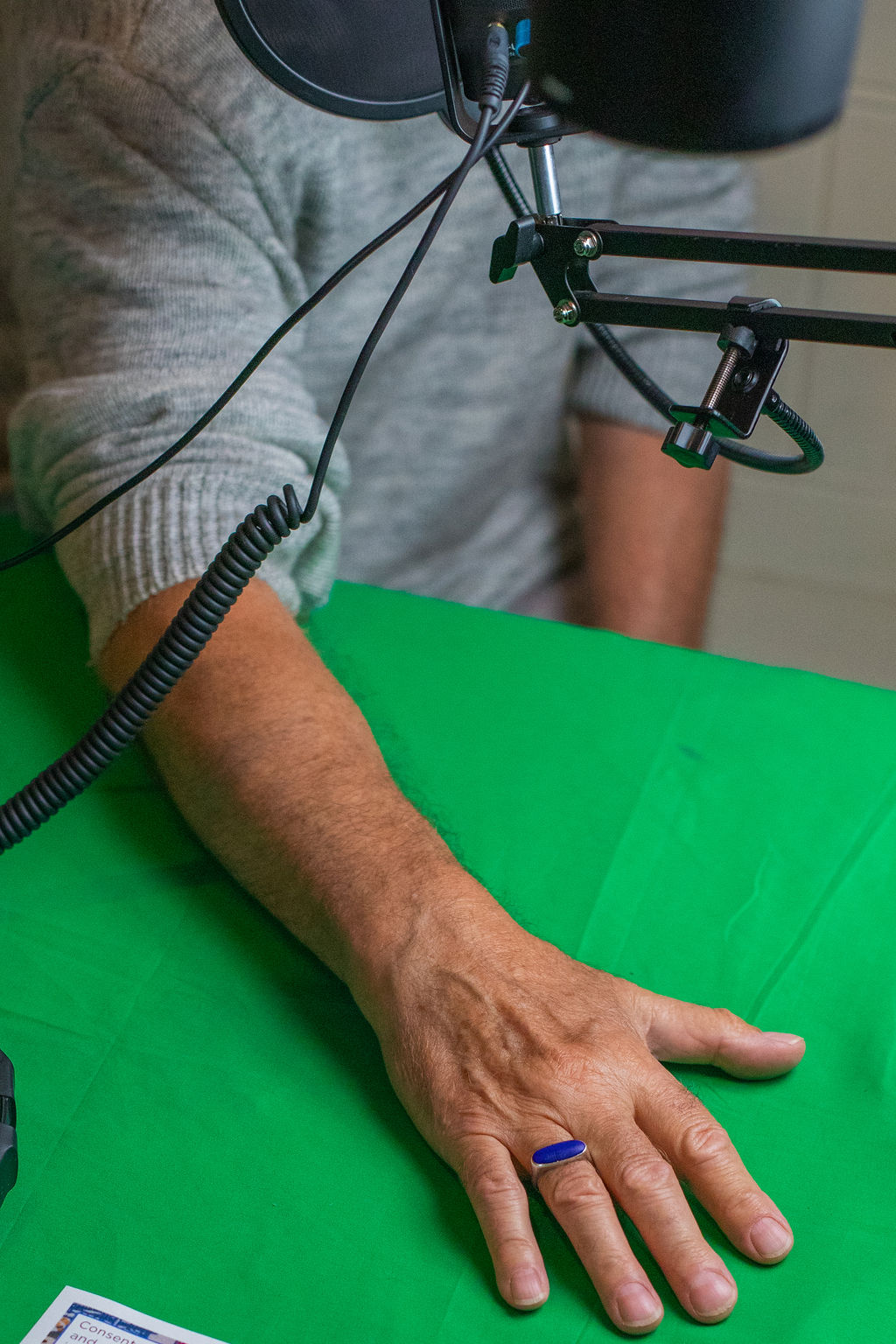 A man's hand showing off his blue stone ring, while talking into some audio recording equipment.