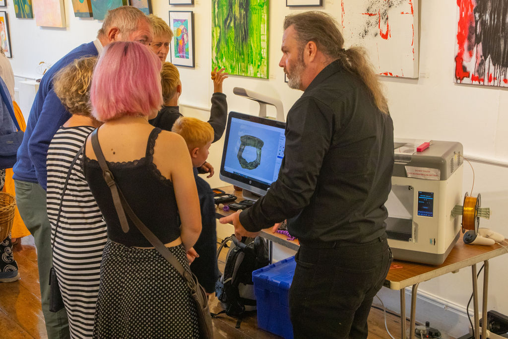 A man showing a group of people some 3D printing technology.